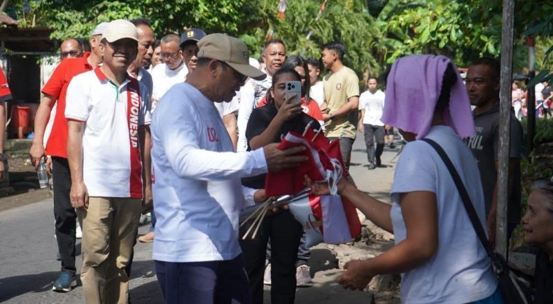 Plt Bupati Heronimus Makainas membagikan bendera ke masyarakat di seputaran Ondong. (foto: Kominfo Sitaro)