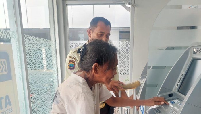 Satpam BRI Cabang Tahuna, Riko Sulengena, membantu nasabah lanjut usia yang kesulitan berjalan saat memasuki Gallery ATM BRI Cabang Tahuna. (Foto: Ist)